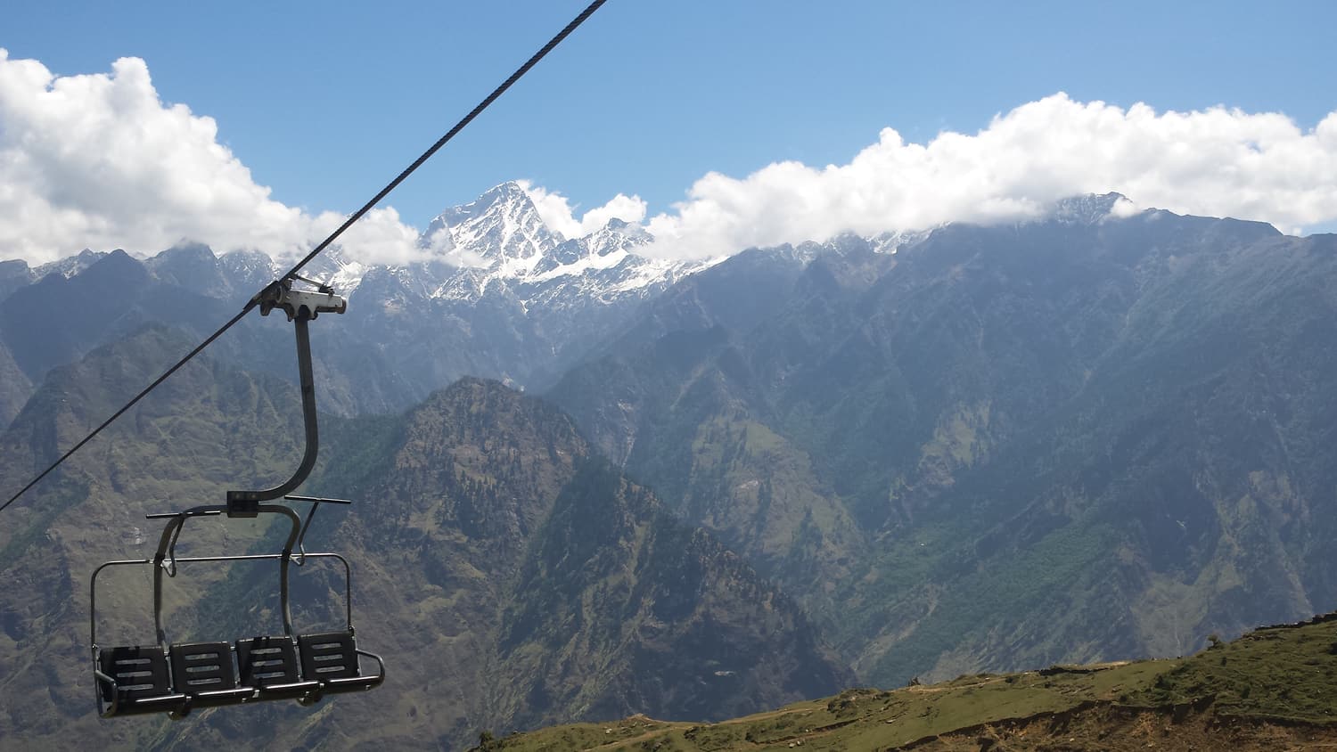 A chairlift at Auli with a wall of snow-covered Himalayan peaks behind
