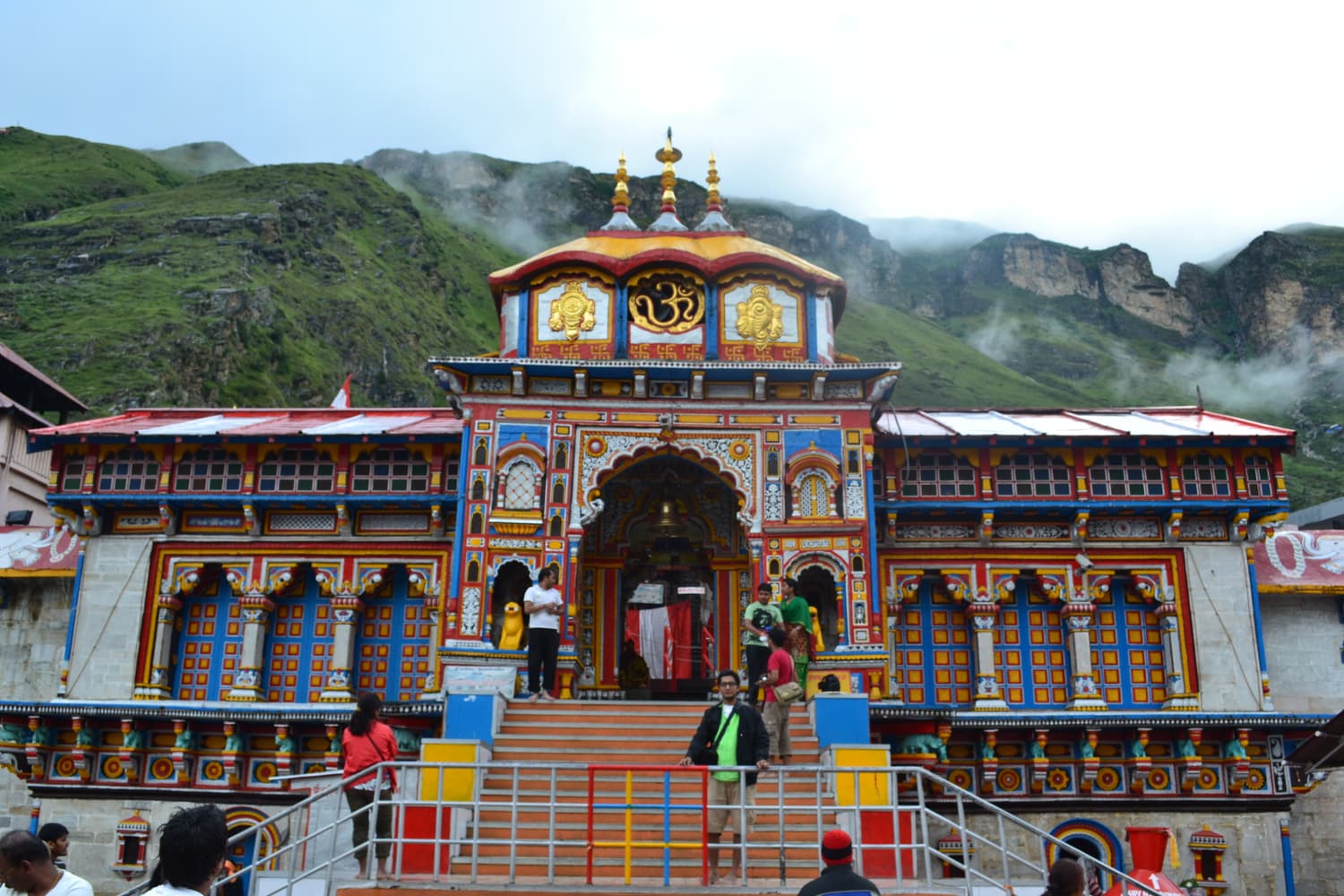 The brightly painted facade of the Badrinath temple with pilgrims on its steps