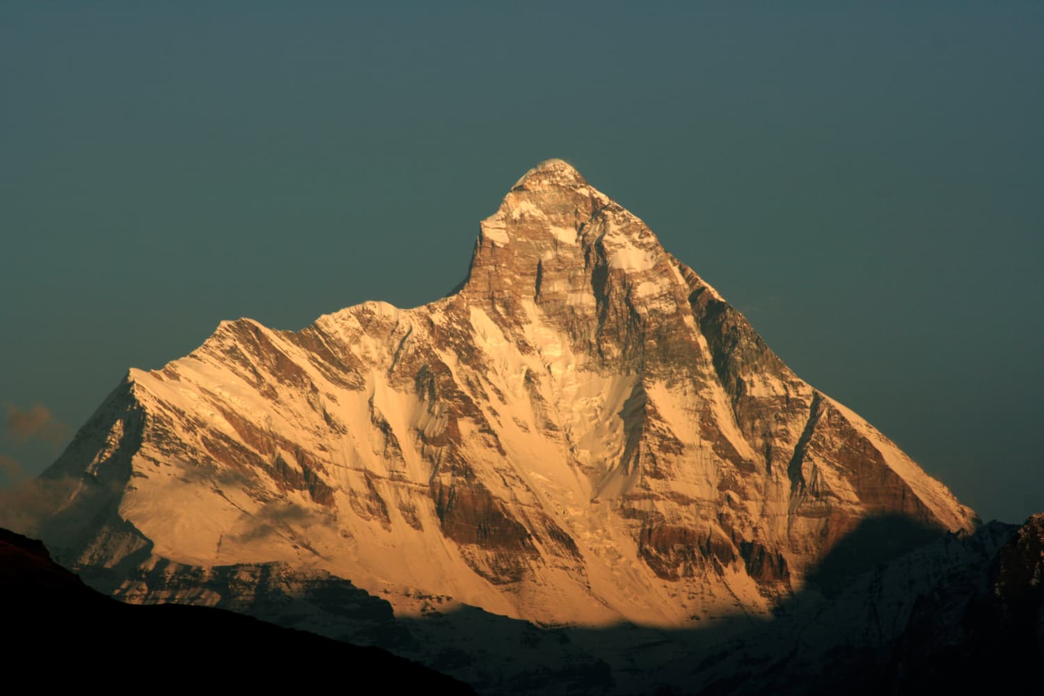 The summit of Nanda Devi glowing orange in low sunlight