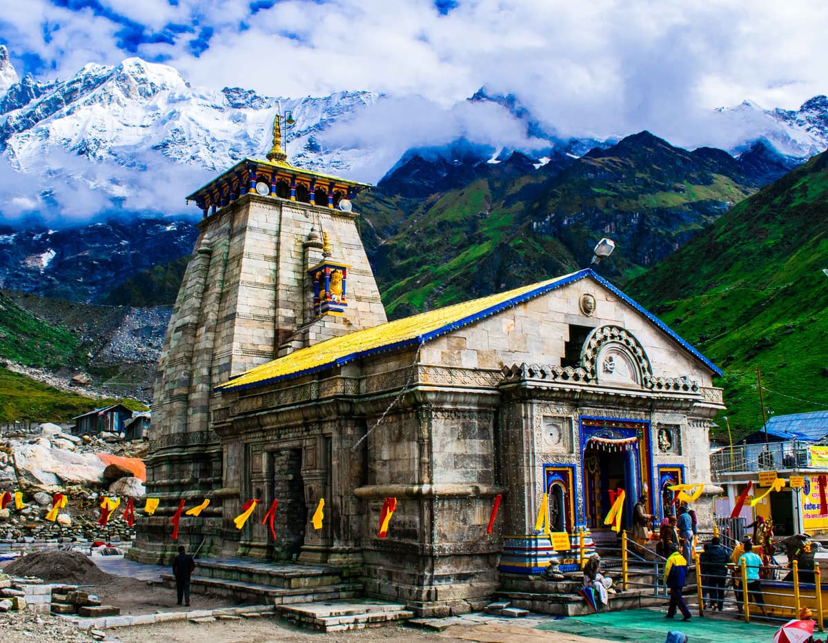 The stone temple of Kedarnath with snow peaks behind it in the monsoon